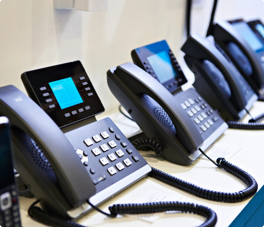 Four business phones side by side atop a desk.