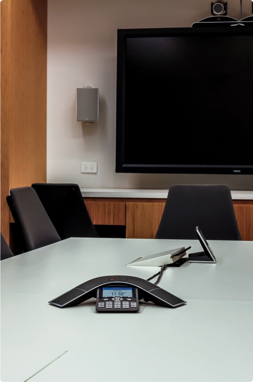 Meeting room of an office with a dial-in solution and a large TV mounted on the wall.