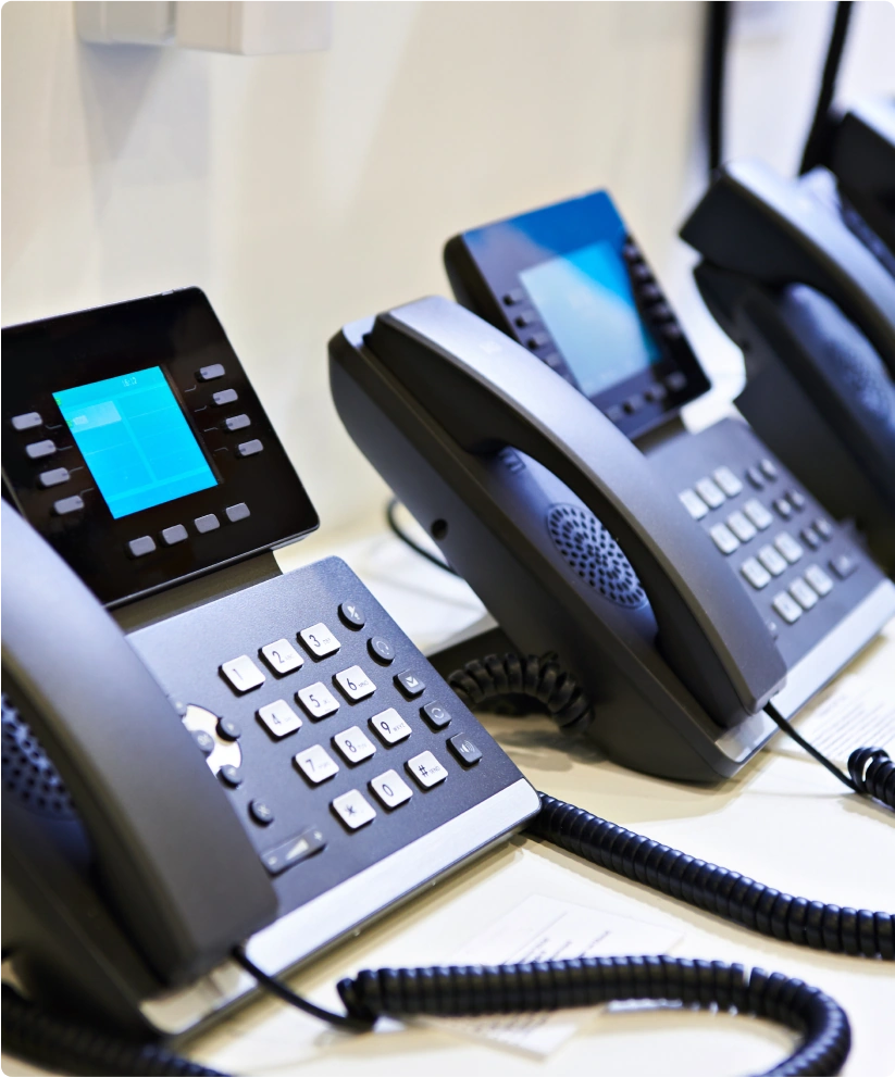 Two business phone systems sit side by side on a desk.