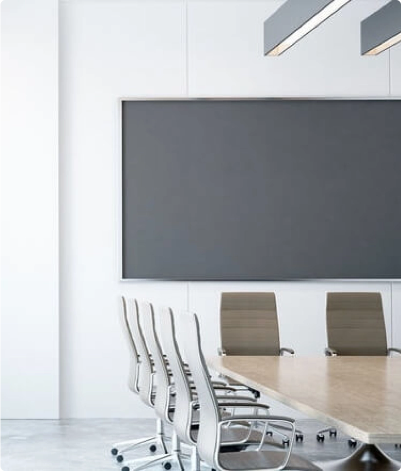 Modern meeting room with a large TV and at least 7 chairs at a large table.