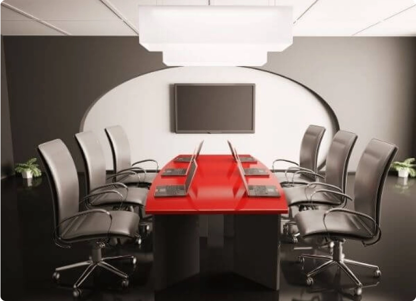 An office meeting room with 6 chairs, 6 laptops, and a TV installed on the wall.