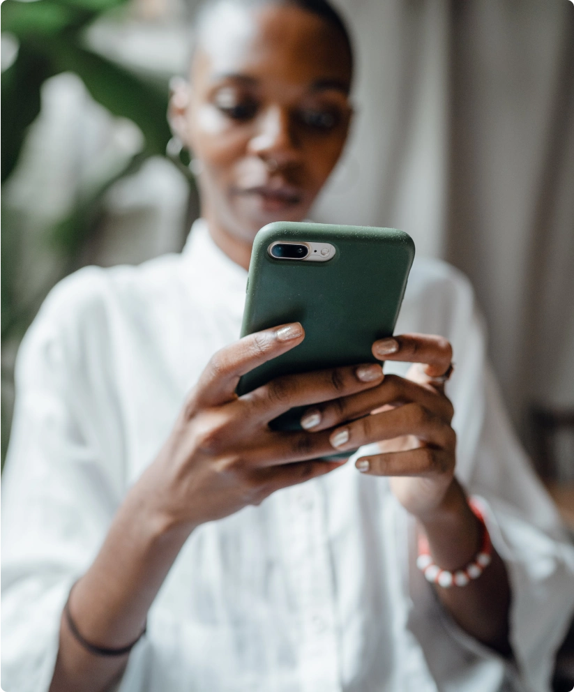 A woman holds an iPhone with a green case.