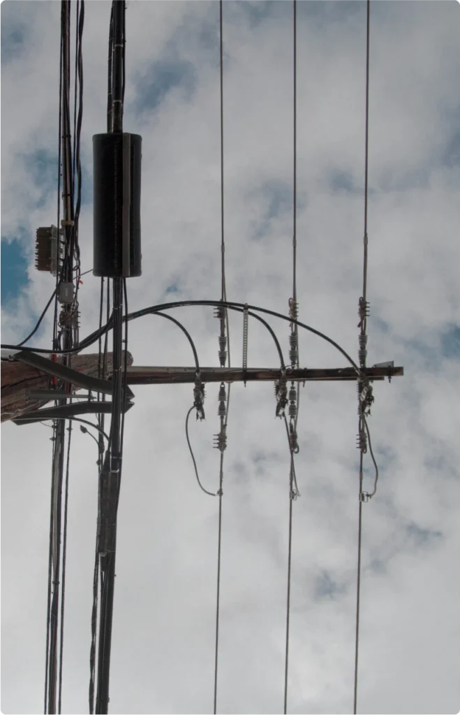 View of a power line from below. Above the power line is a cloudy sky.